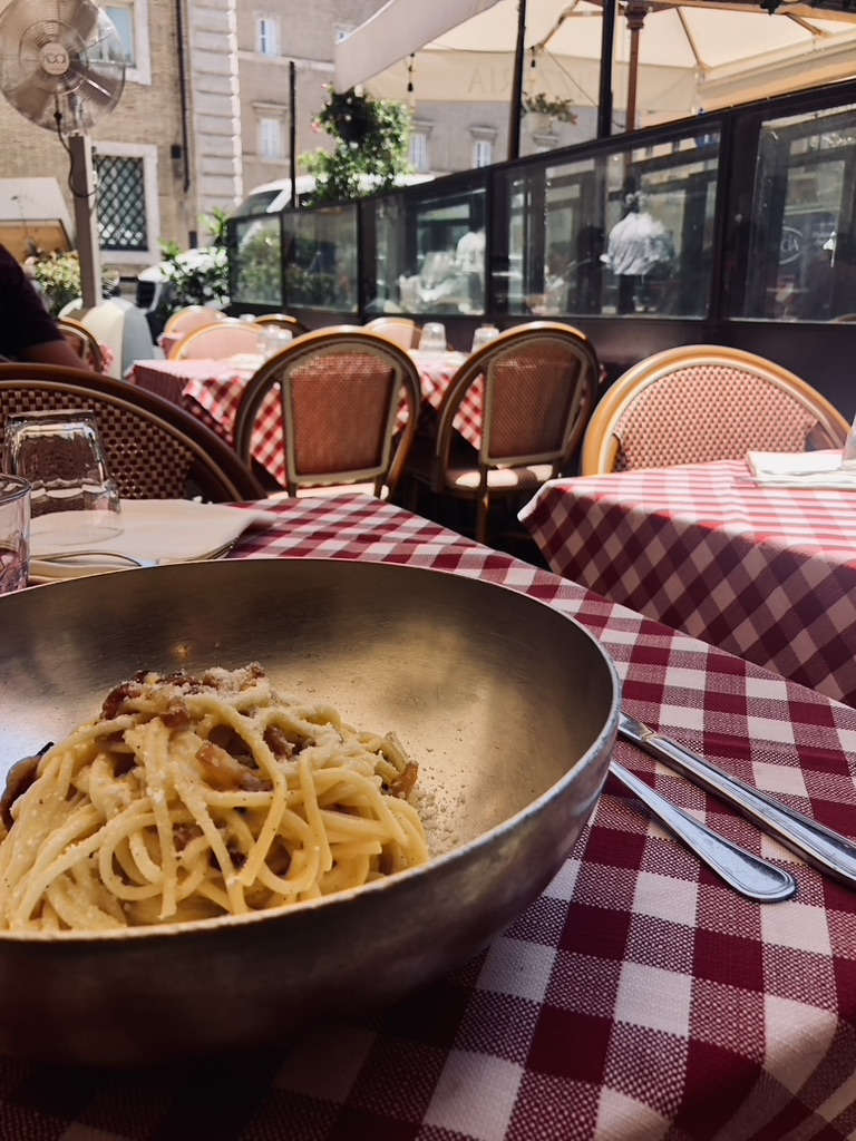 Pasta dish served in a pan with checkered tablecloth at a restaurant in Rome, Italy