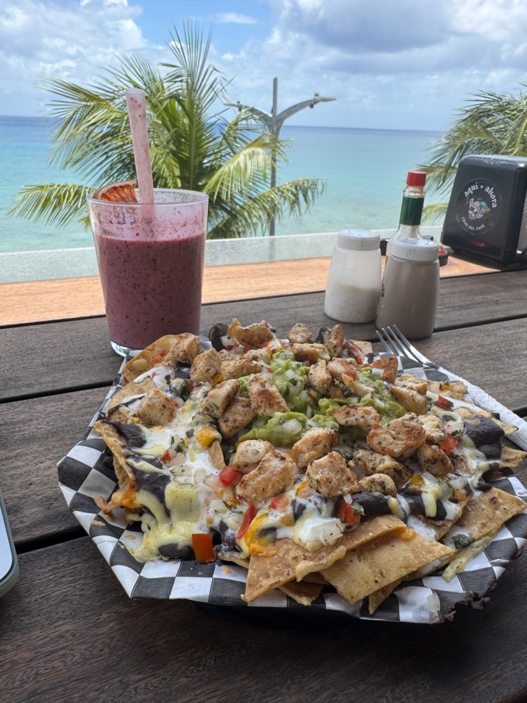 View of ocean with chicken nachos, guacamole and smoothie at Aqui + Ahora restaurant in Cozumel, Mexico