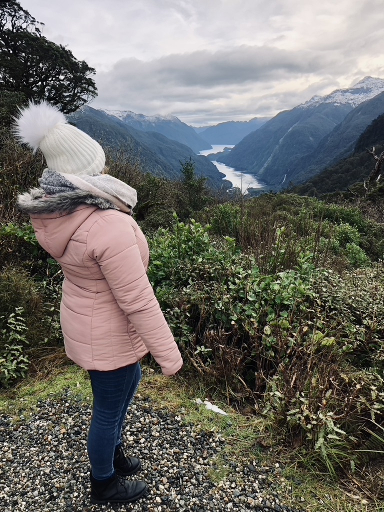 Girl in pink jacket looking out at view of Doubtful Sound, New Zealand