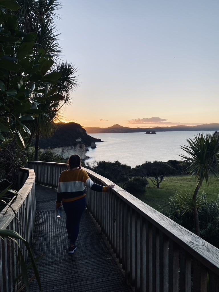Girl looking out at sunset over Cathedral Cove in New Zealand