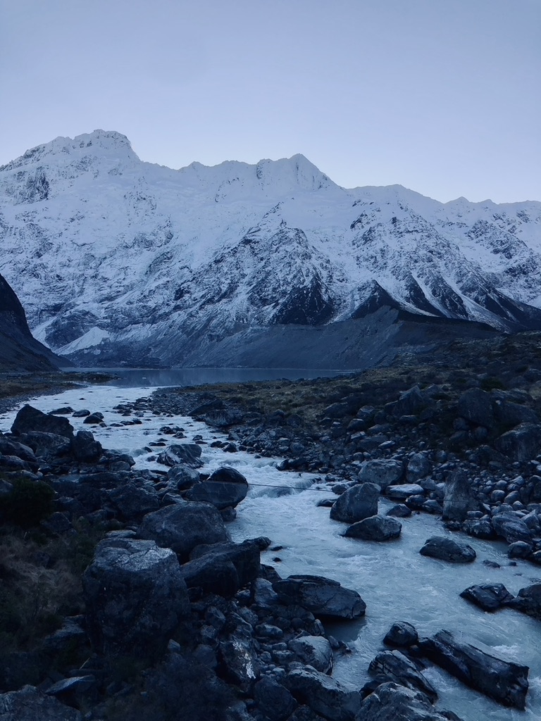 Waterfall with snow capped mountains on the Hooker Valley Track, New Zealand