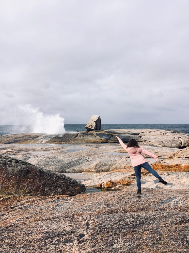 Girl pointing to water spraying out of blow hole in Bicheno, Tasmania