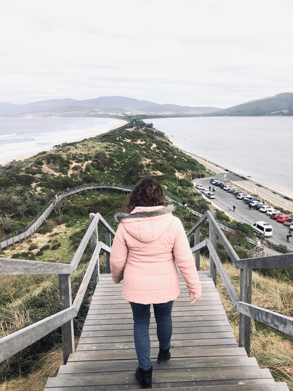 Girl in pink coat looking out over The Neck on Bruny Island in Tasmania, Australia