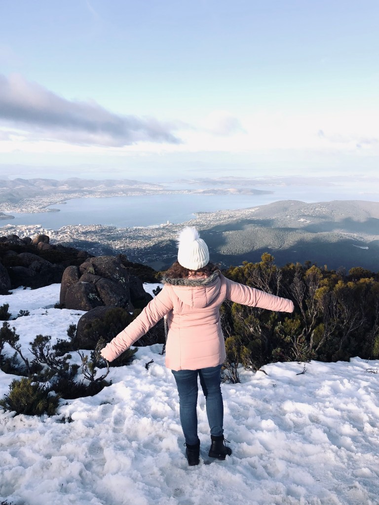Girl in pink coat standing on snow on the top of Mt Wellington in Hobart, Tasmania
