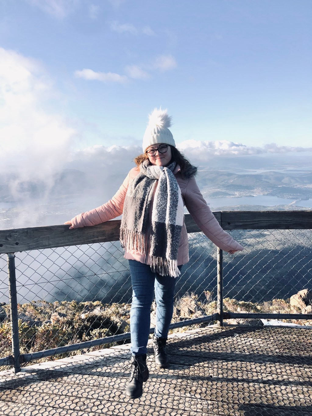 Girl in pink coat smiling on the top of Mt Wellington in Hobart, Tasmania