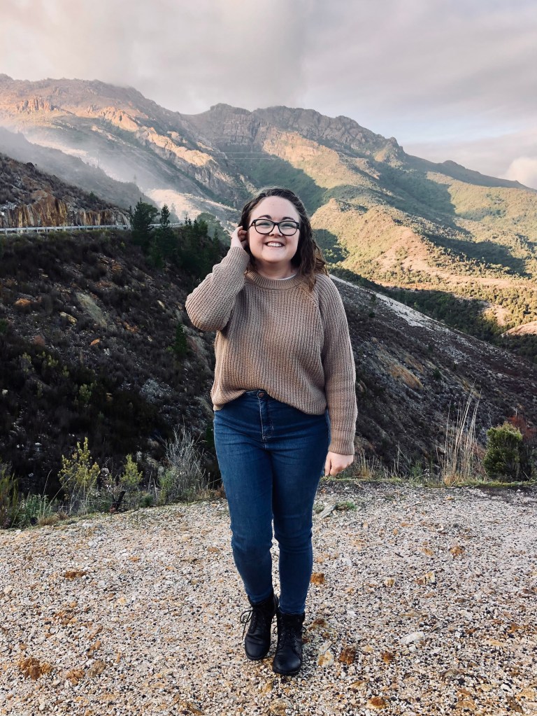 Girl in brown sweater smiling on a stop on a road trip in Tasmania
