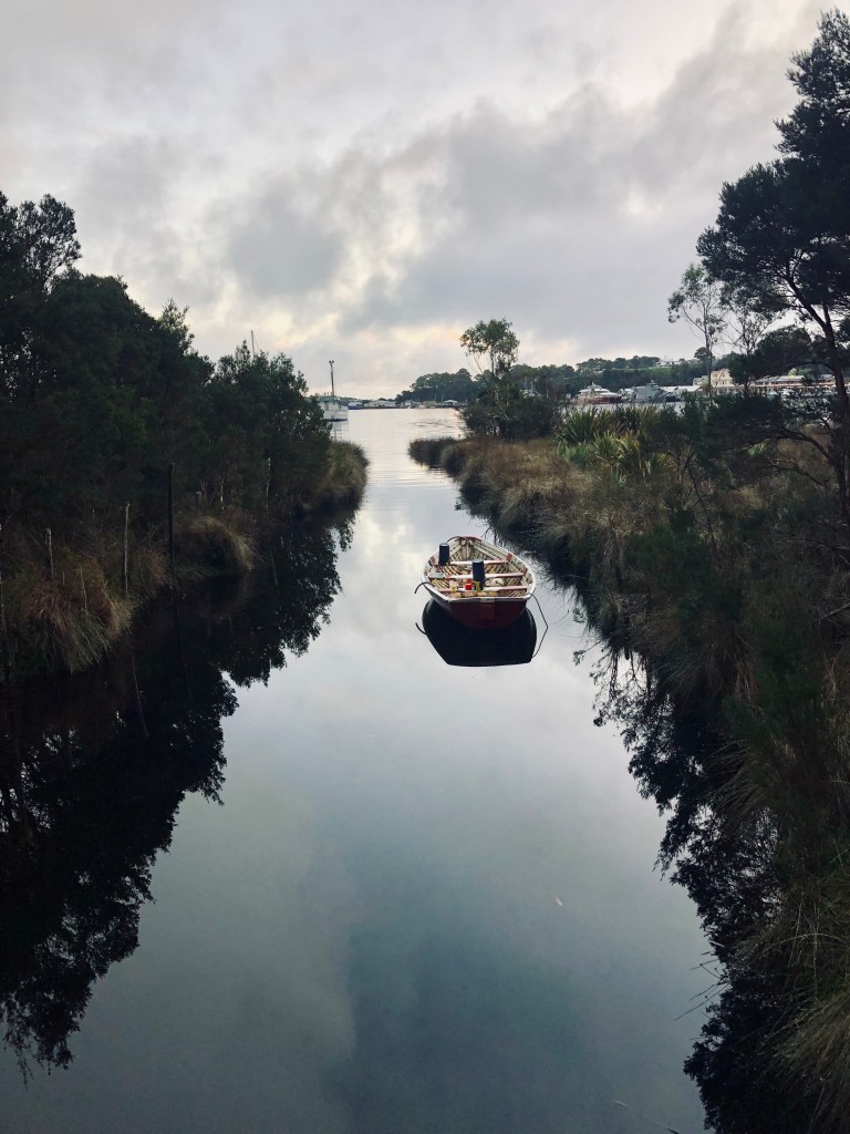 Boat in water in Strahan lake with beautiful reflection in Tasmania