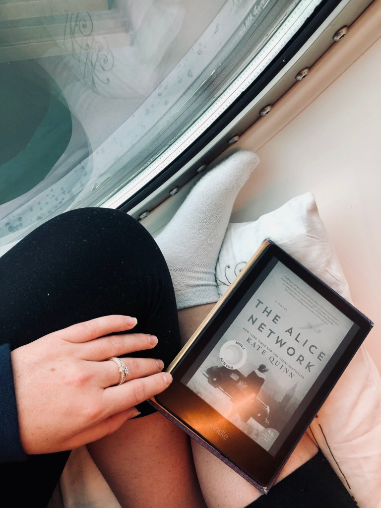 Girl reading kindle while sitting in a port hole on a disney cruise ship