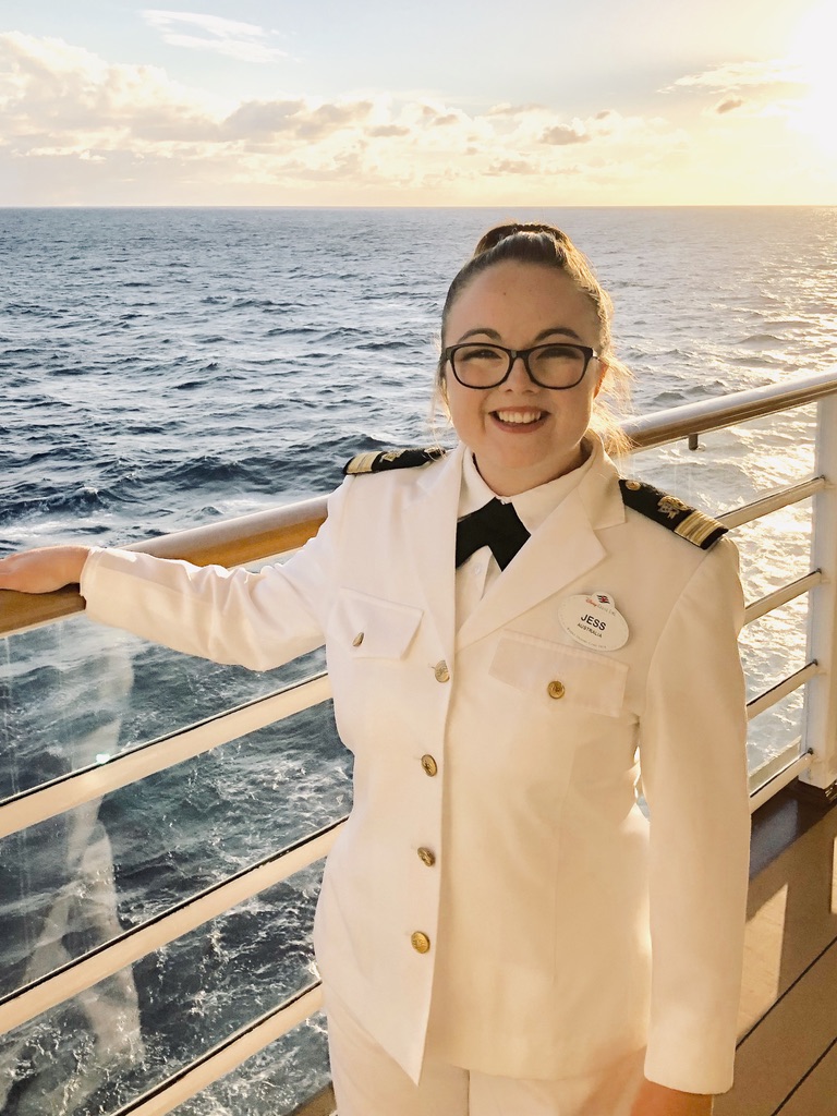 Disney Cruise Line Crew Member dressed in Officer whites posing on deck at sunset with ocean in background