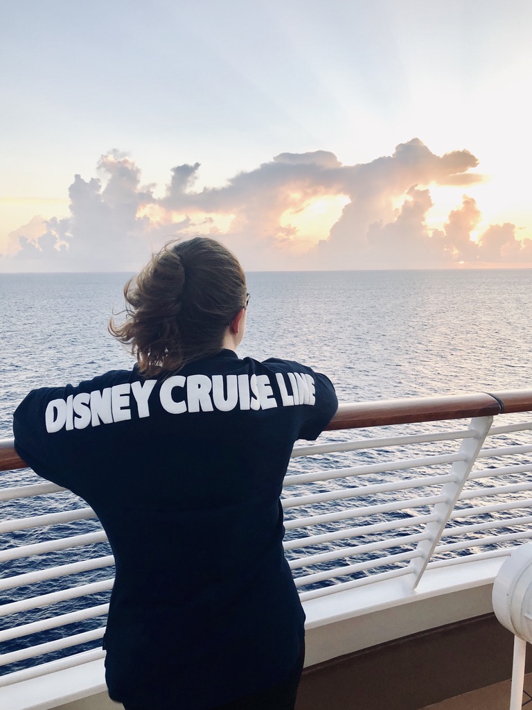 Girl wearing Disney cruise line spirit jersey looking out over sunrise on the ocean
