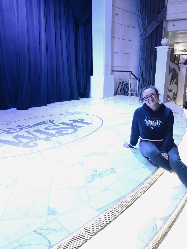 Girl sitting on Disney Wish stage on disney cruise