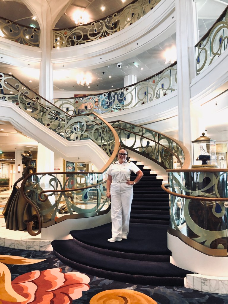 Disney Cruise Line officer standing on staircase in Grand Hall on the Disney Wish