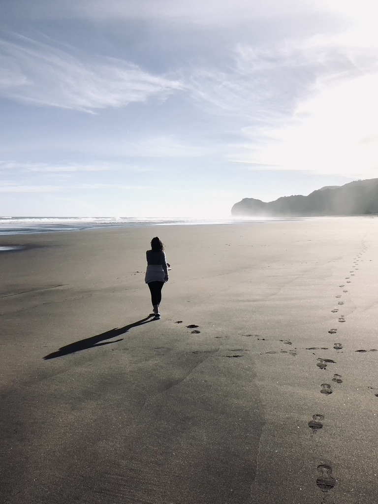 Girl walking on sand at the beach in New Zealand's North Island
