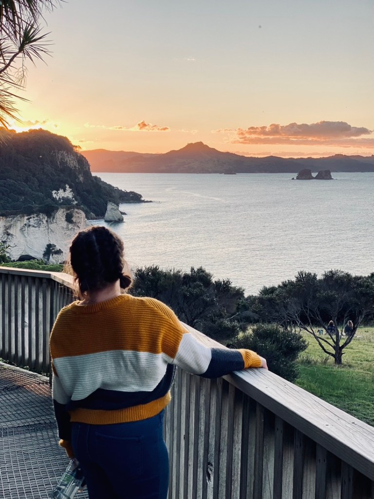 Girl looking out at sunset at Cathedral Cove in New Zealand's North Island