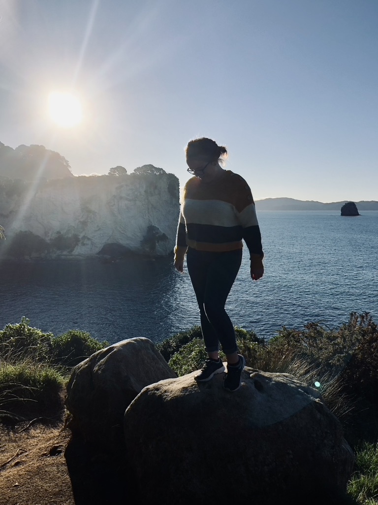 Girl standing on a rock at sunset at Cathedral Cove in New Zealand's North Island