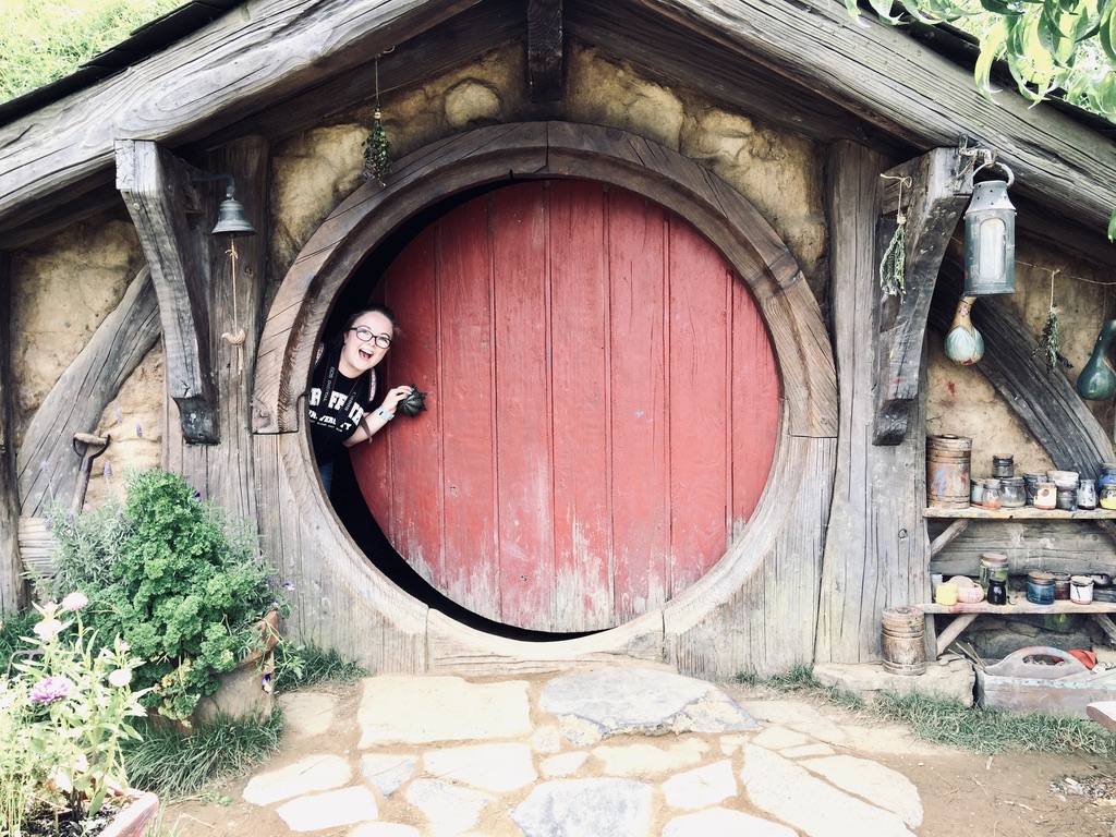Girl peaking out hobbit hole door at Hobbiton in New Zealand