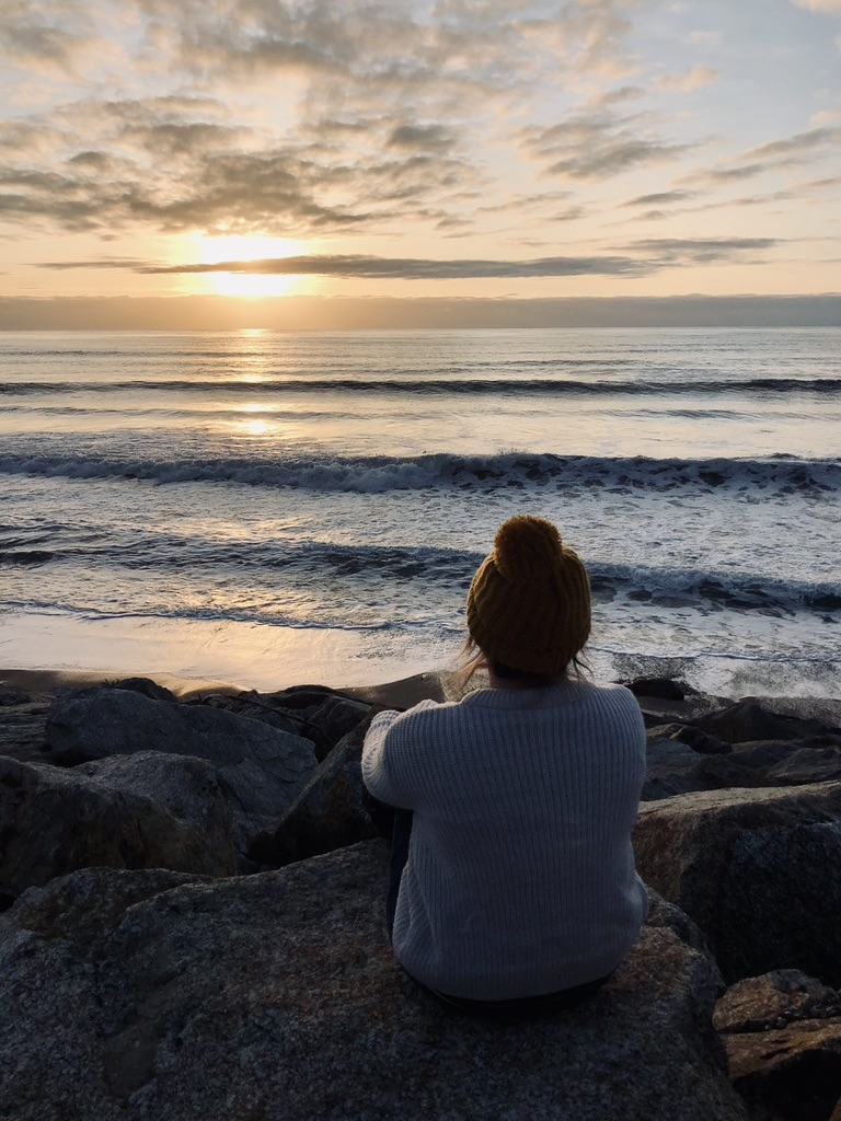 Girl looking out at sunset on ocean in New Zealand