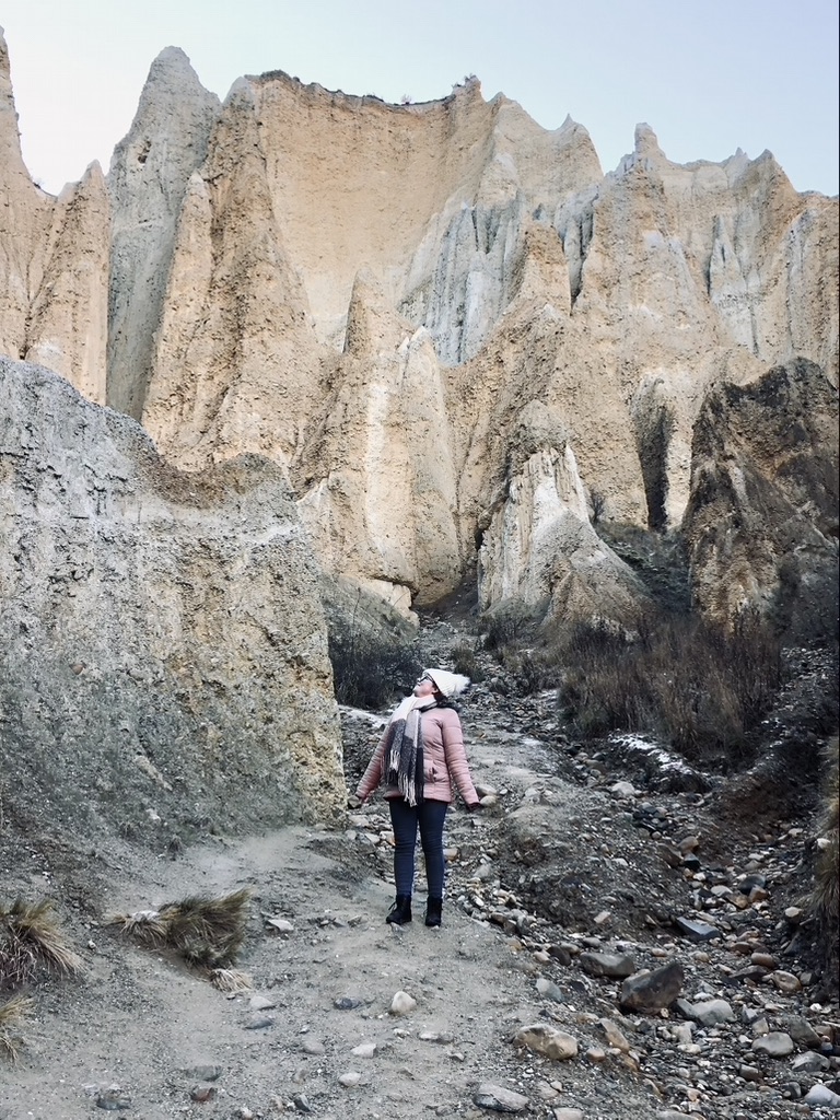 Girl looking up at unusual rock formations at Clay Cliffs, New Zealand