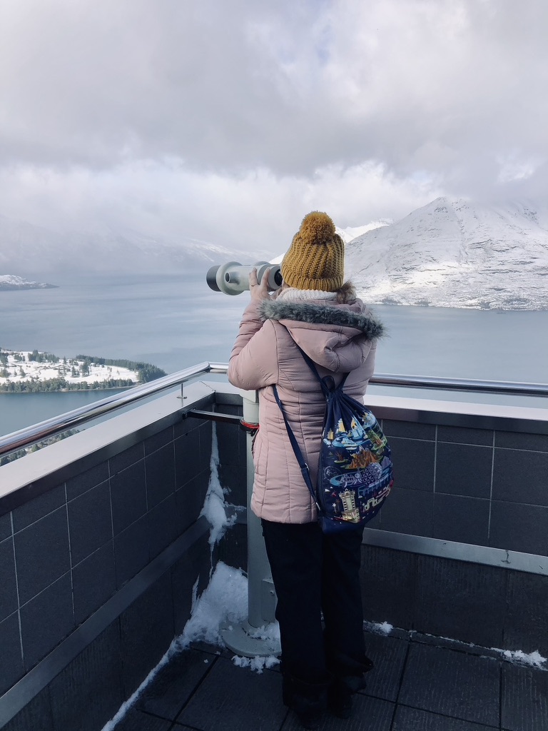 Girl looking out with binoculars the observation deck over Queenstown, New Zealand