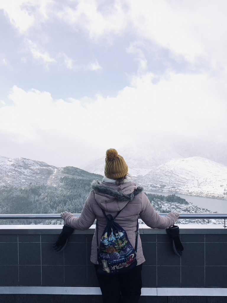 Girl looking out over view of snowy city in Queenstown, New Zealand