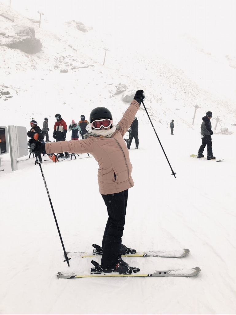Girl in pink jacket in skis at the top of beginner slope at the Remarkables, Queenstown, New Zealand