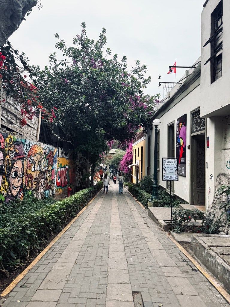 Pedestrian street in Barranco, Peru with street art and trees along the walkway