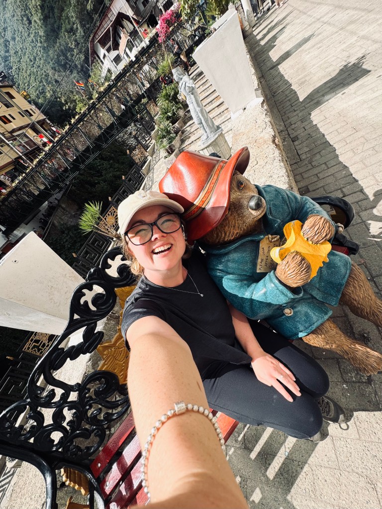 Girl taking selfie with famous Paddington in Peru statue in Aguas Calientes, Peru