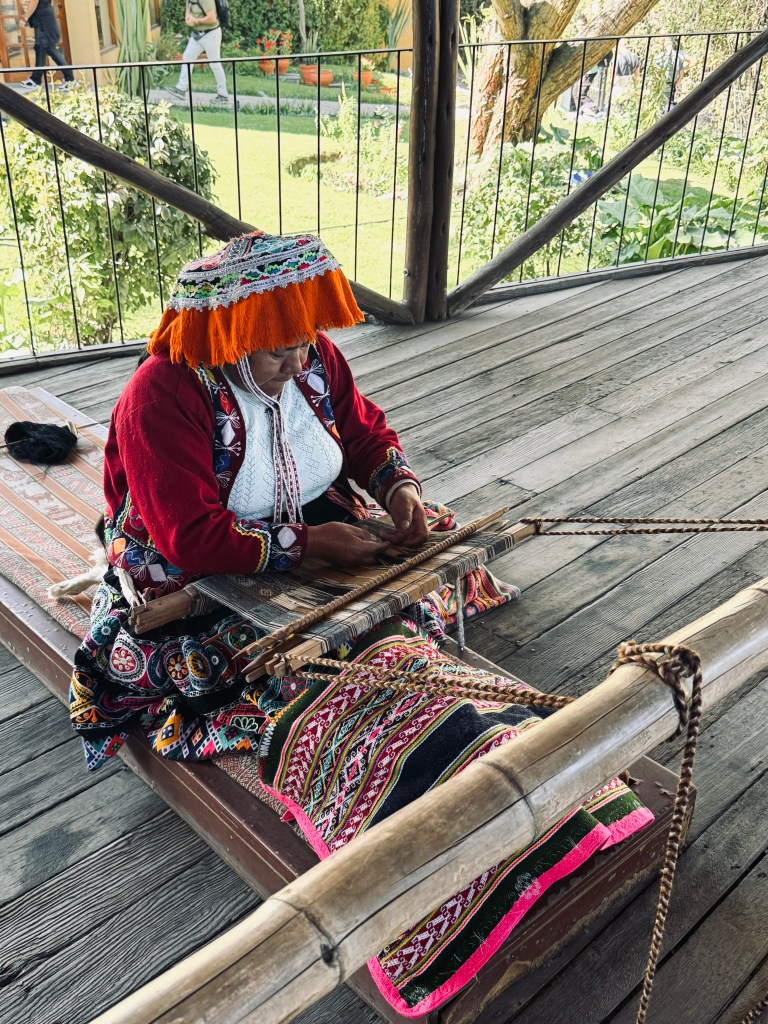 Lady dressed in a traditional Peru outfit, weaving alpaca wool at Mundo Alpaca in Arequipa, Peru
