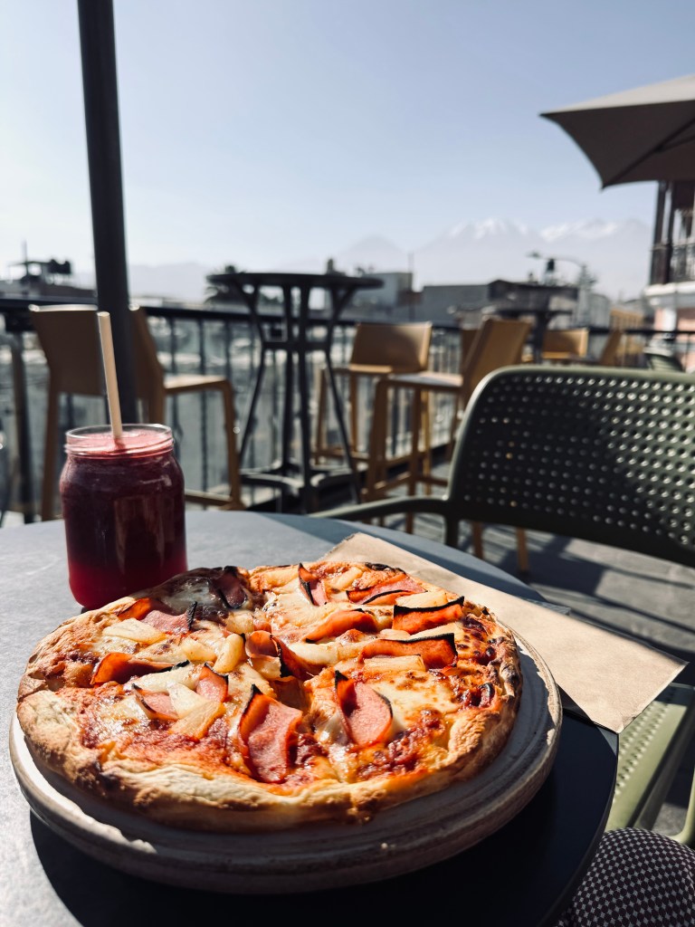 Pizza and juice on a rooftop restaurant with views of snow capped mountains in the background in Arequipa, Peru