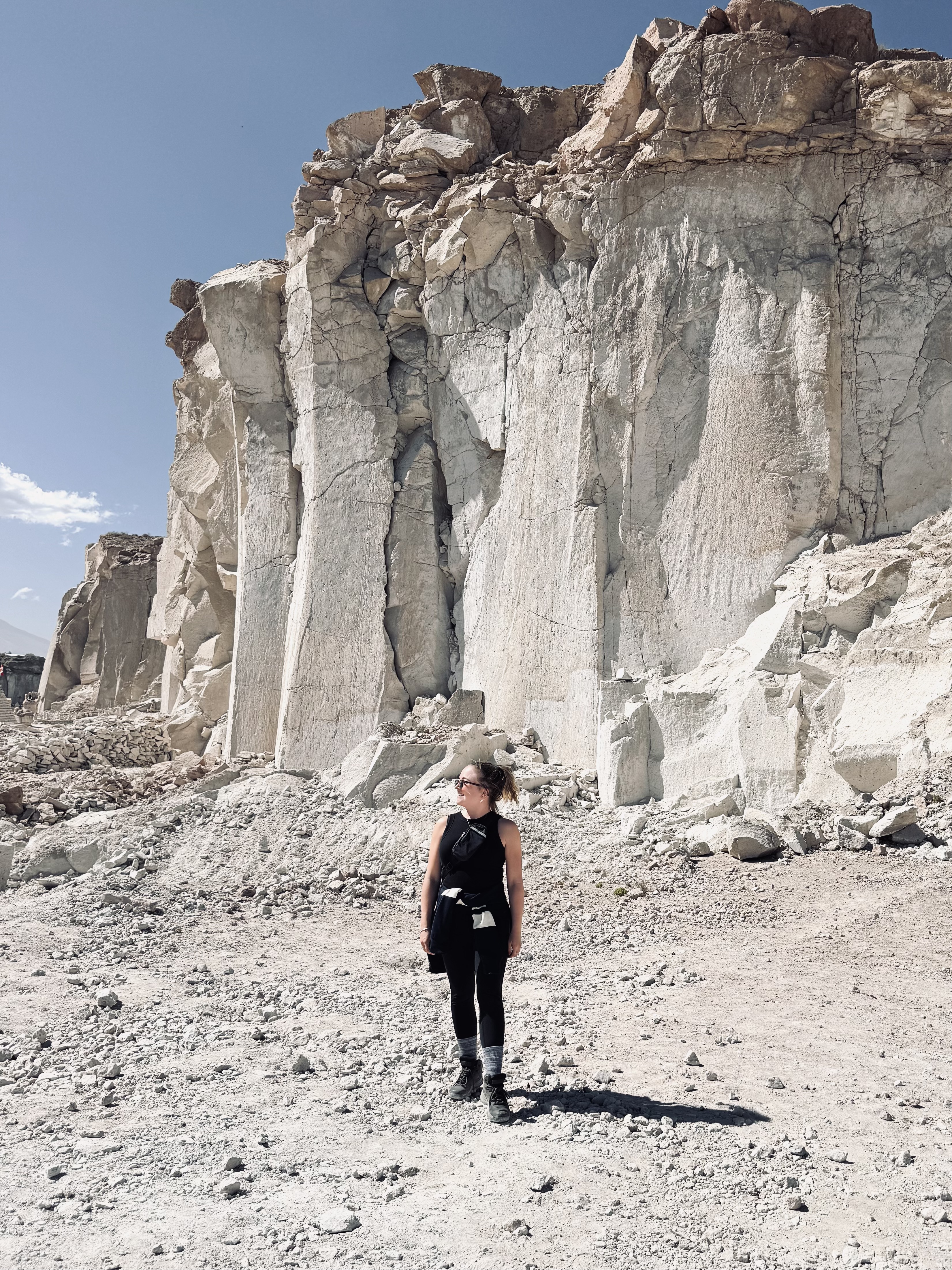Girl standing in front of tall cliff of sillar stone at Ruta del Sillar in Arequipa, Peru