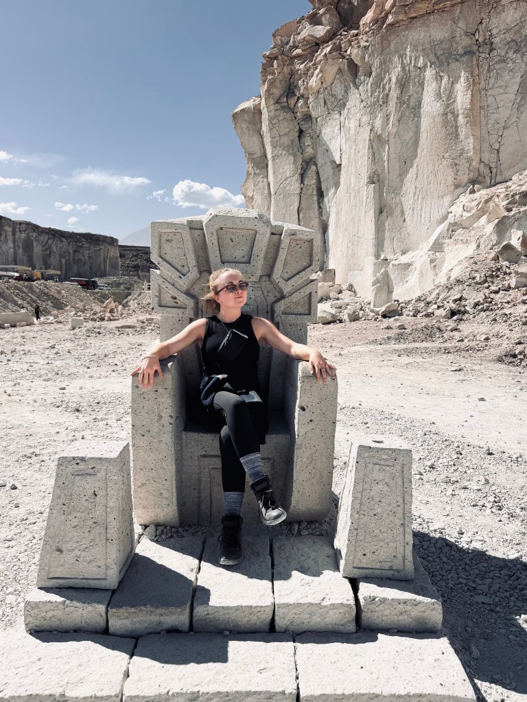 Girl sitting on carved stone throne at Ruta del Sillar in Arequipa, Peru
