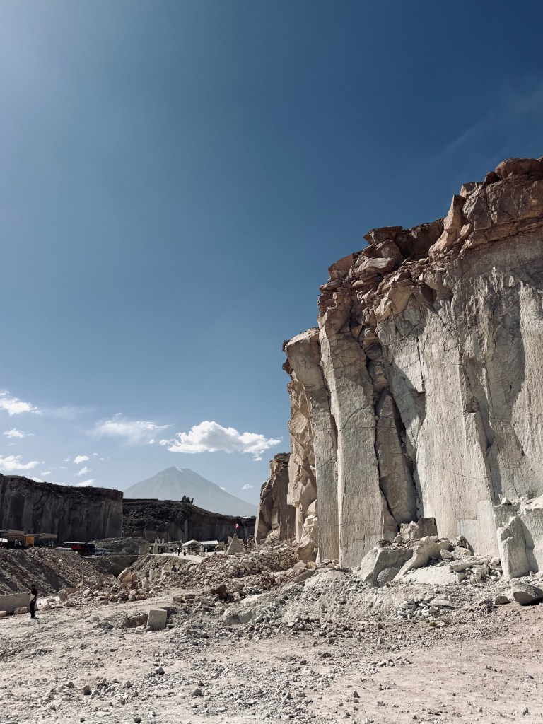 Stone cliffs with volcano in background at Ruta del Sillar in Arequipa, Peru