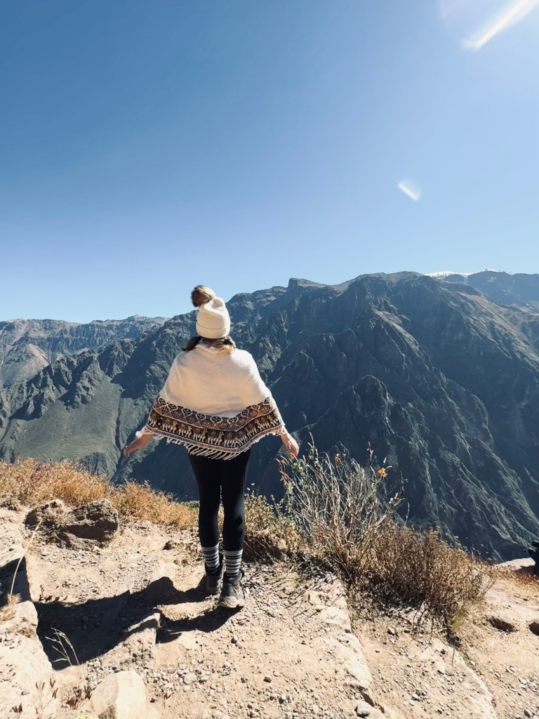 Girl in peruvian poncho looking out at Colca Canyon, Peru