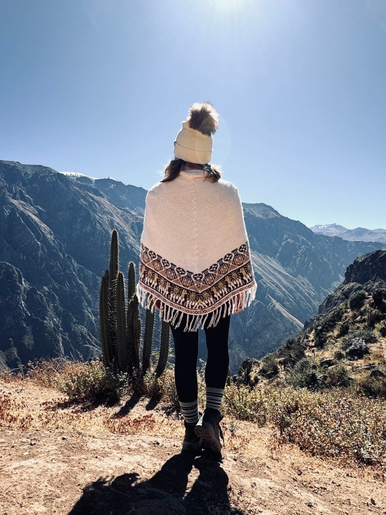 Girl in peruvian poncho looking out at Colca Canyon, Peru