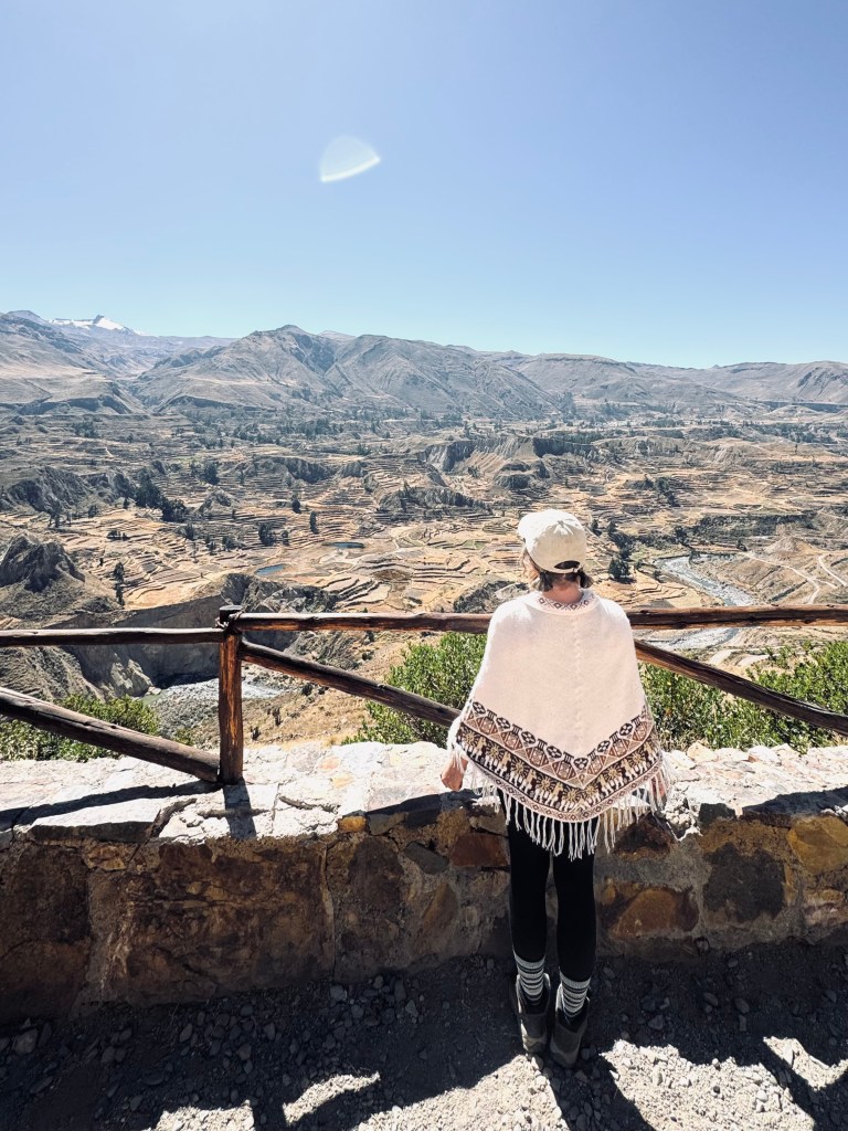 Girl in peruvian poncho looking out at Colca Canyon, Peru