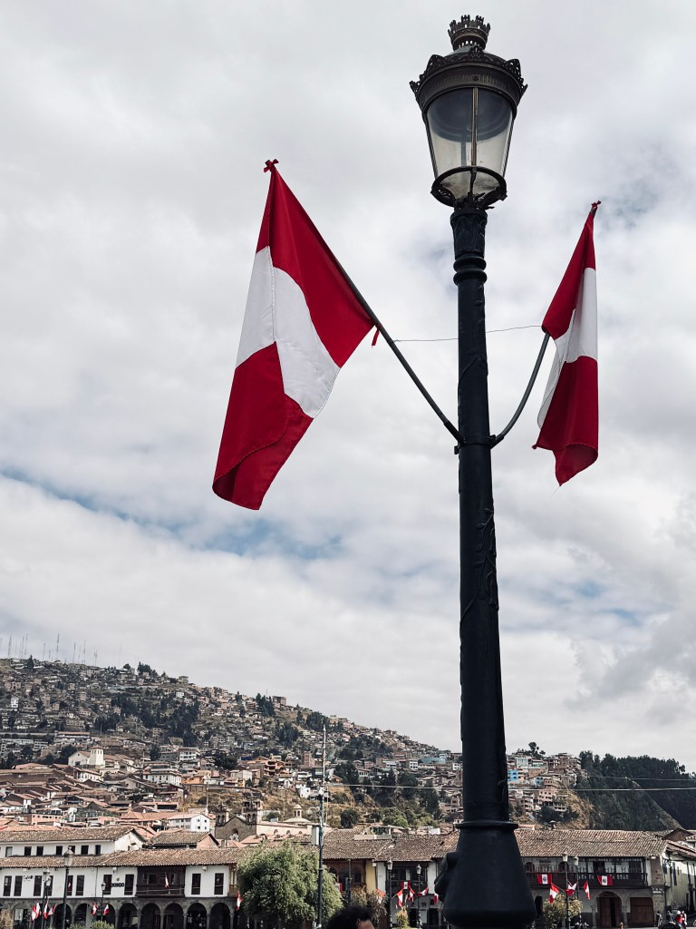 Peruvian flats on a lamp post with view of Cusco city in background in Peru