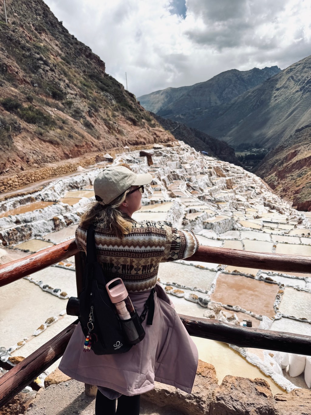 Girl in llama sweater looking out at the Maras Salt Mines in Peru