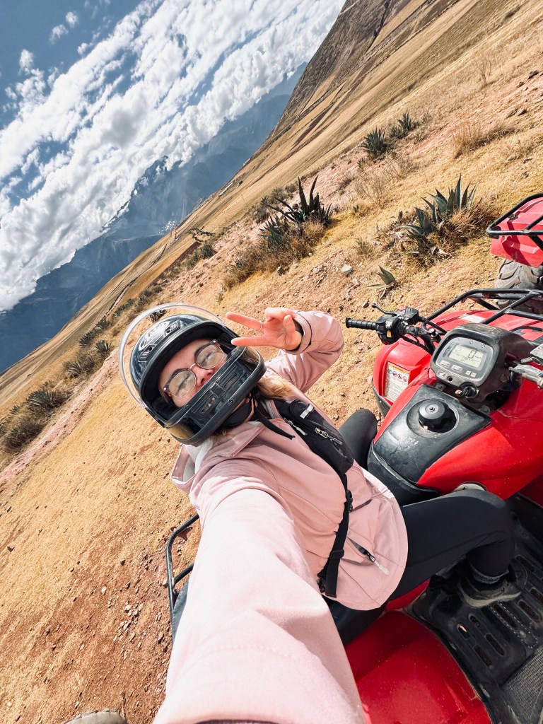 Girl taking selfie on an ATV with Andes mountains in the background in Peru