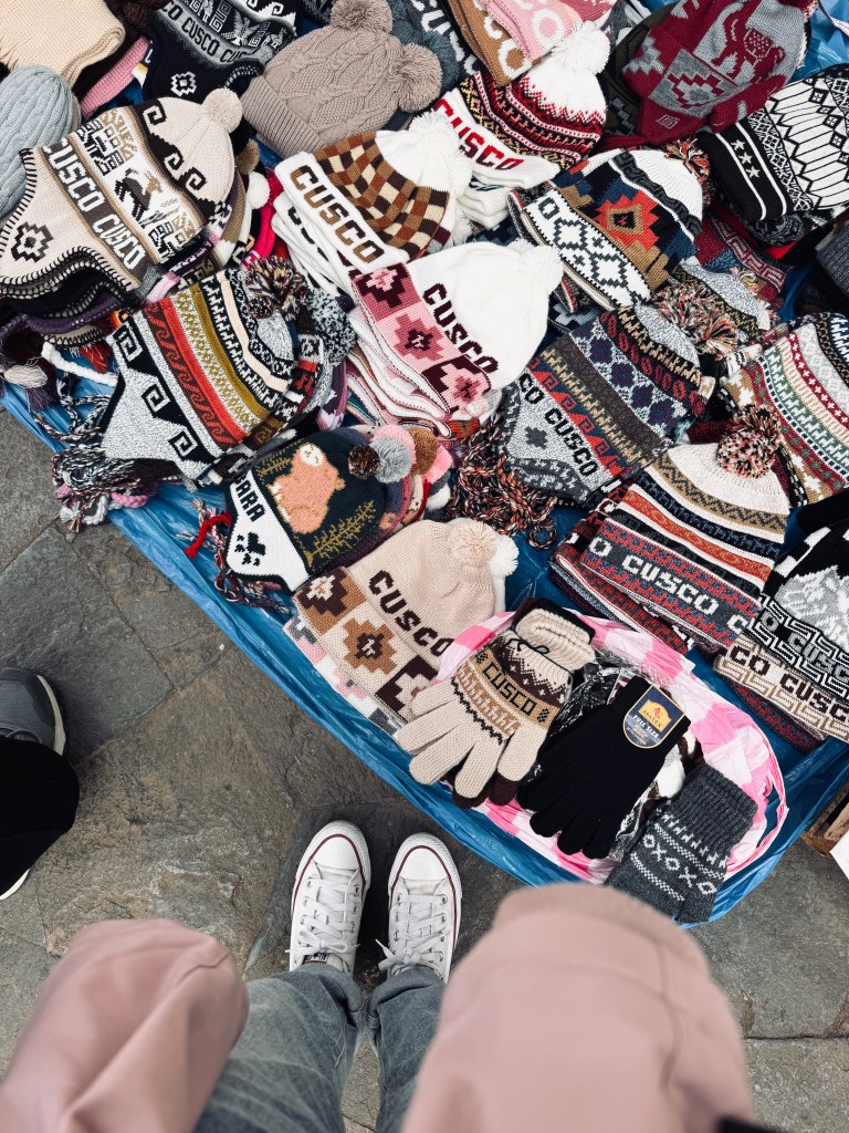 Market stall on the ground with a variety of Cusco souvenirs including beanies and gloves in Peru