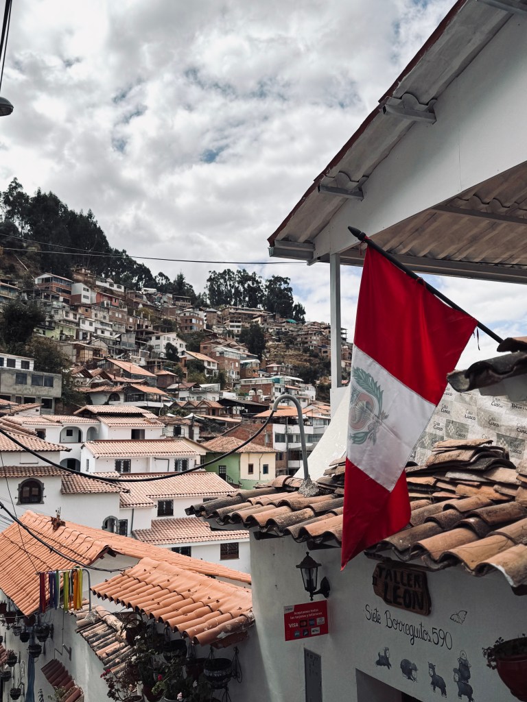 Cute street with peruvian flags and view of city in background in San Blas neighbourhood in Cusco, Peru