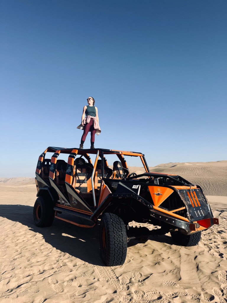 Girl standing on dune buggy in desert in Huacachina, Peru