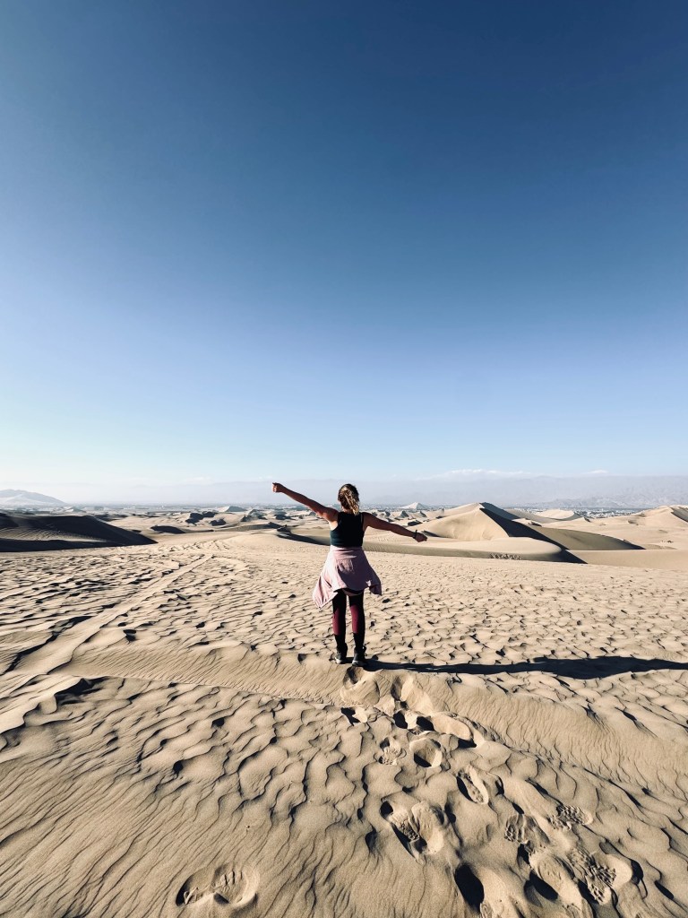 Girl looking out over desert with sand dunes in background in Huacachina, Peru