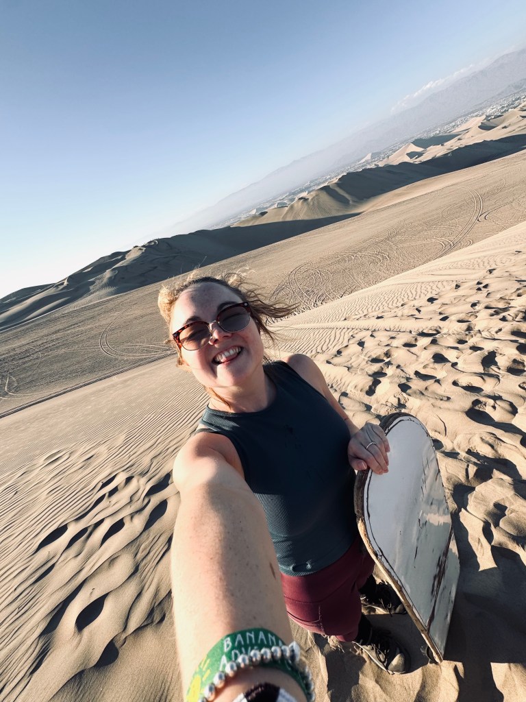 Girl taking selfie with sand board in the desert Huacachina, Peru