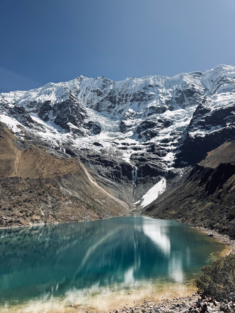 Aqua blue glacier lake water under a huge snow covered mountain at Humantay Lake, Peru