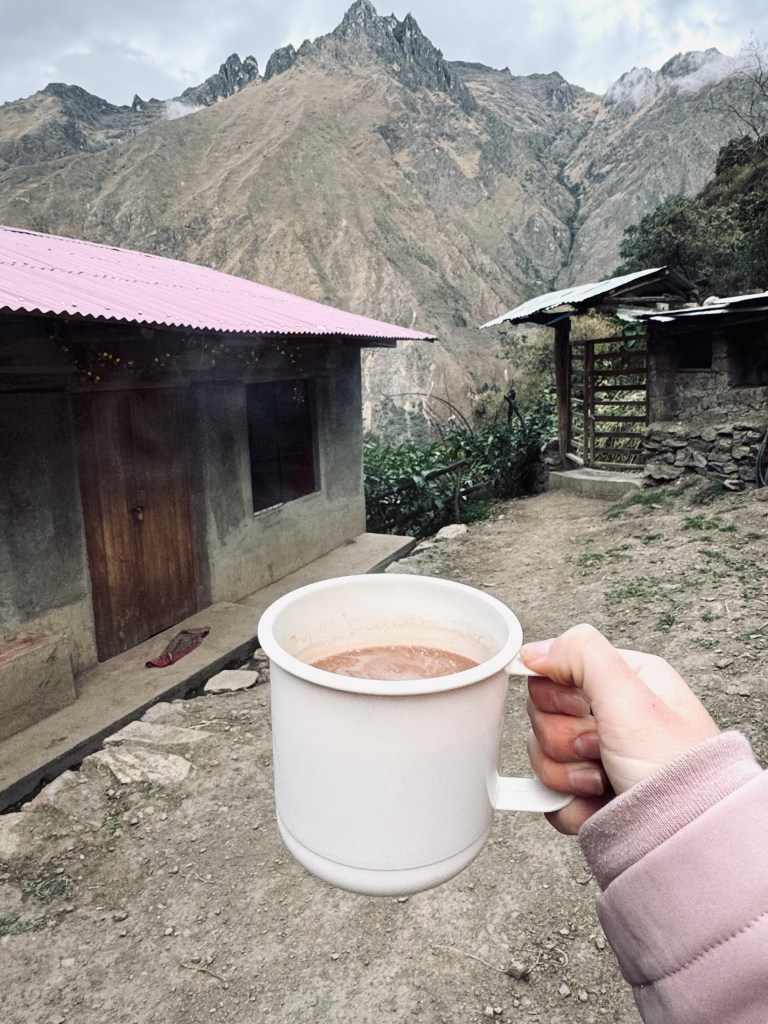 Hand holding plastic mug of hot chocolate at camp on the Inca Trail, Peru