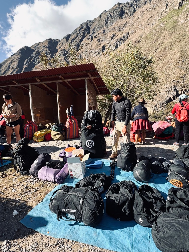 Duffel bags on tarp and porters packing packs on the Inca Trail in Peru