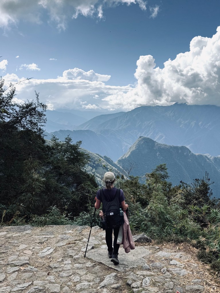 Girl with hiking poles looking out at Machu Picchu mountain on the Inca Trail in Peru