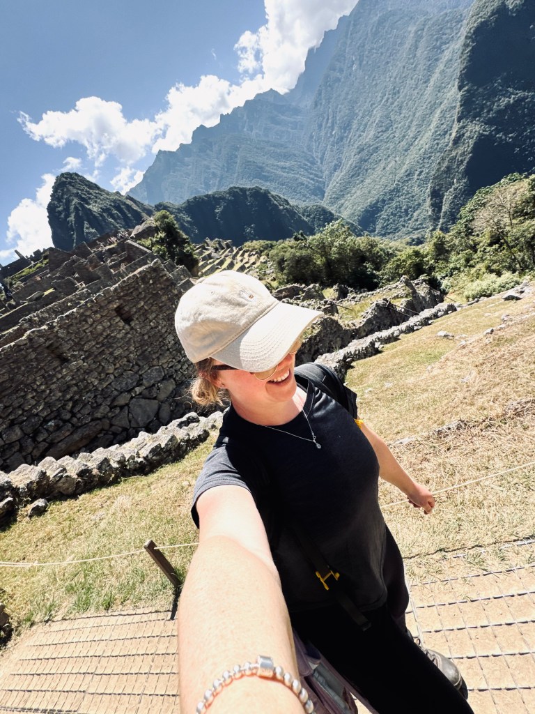 Girl with llama cap taking selfie with Machu Picchu in background on the Inca Trail in Peru