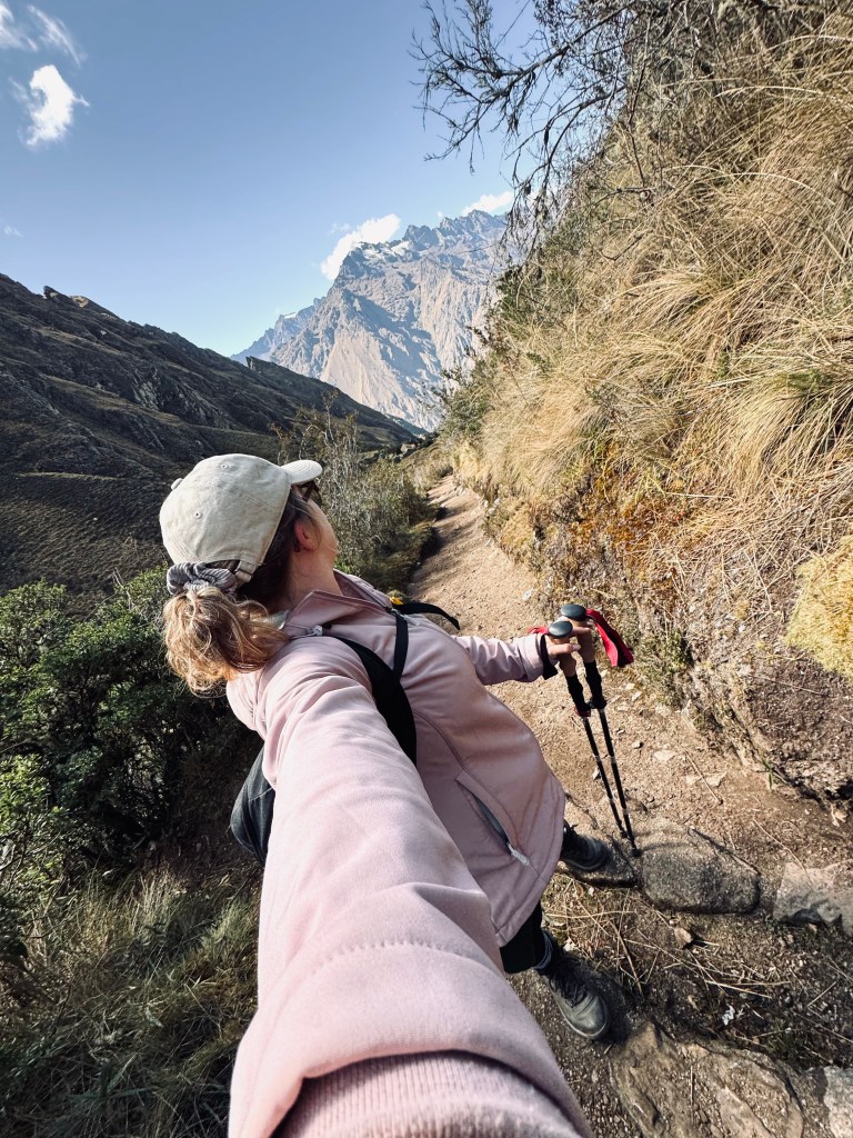 Girl taking selfie looking back at mountains with hiking poles on the Inca Trail in Peru