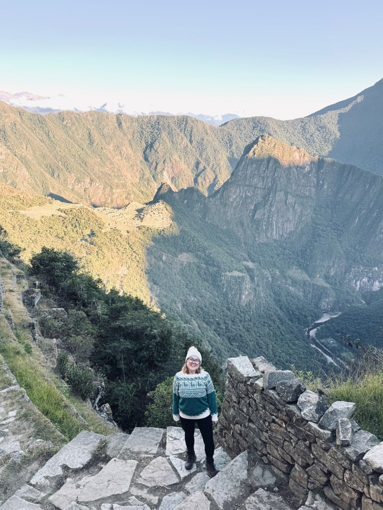 Girl standing with view of Machu Picchu from the Sun Gate at sunrise on the Inca Trail in Peru